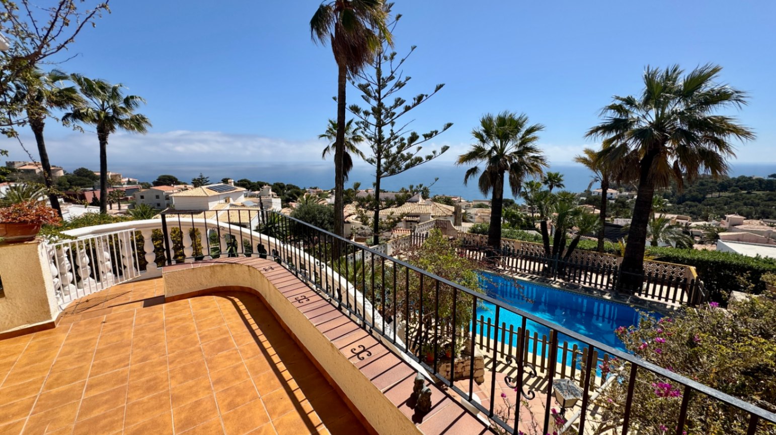 Terraza elevada con baldosas de terracota y barandilla de forja, con vistas panorámicas a la piscina privada y al mar Mediterráneo.