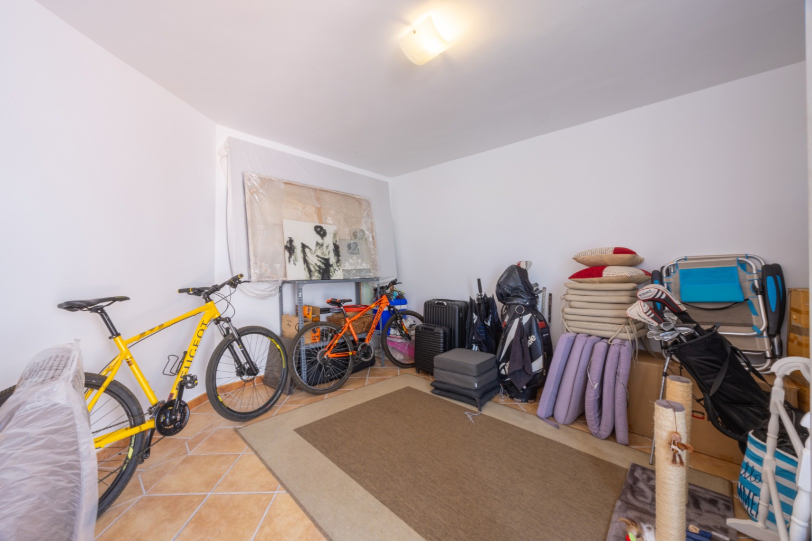 Trastero espacioso con suelo de baldosas cerámicas, ideal para el almacenamiento de bicicletas, equipos deportivos y enseres personales.