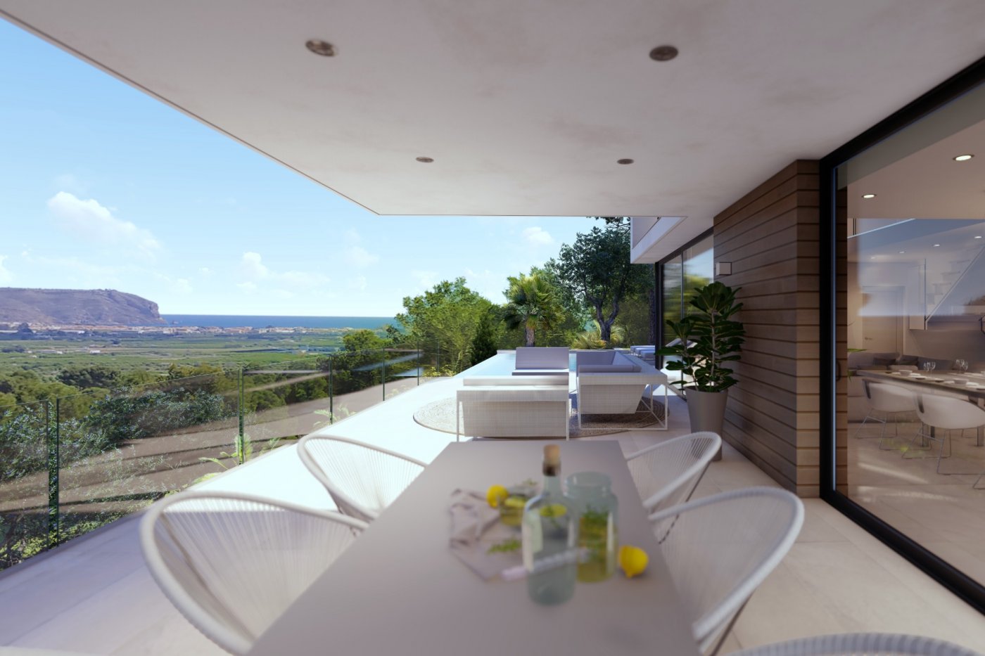 Terraza cubierta con zona de comedor, mobiliario de exterior blanco y barandillas de cristal con vistas panorámicas al valle y al mar.