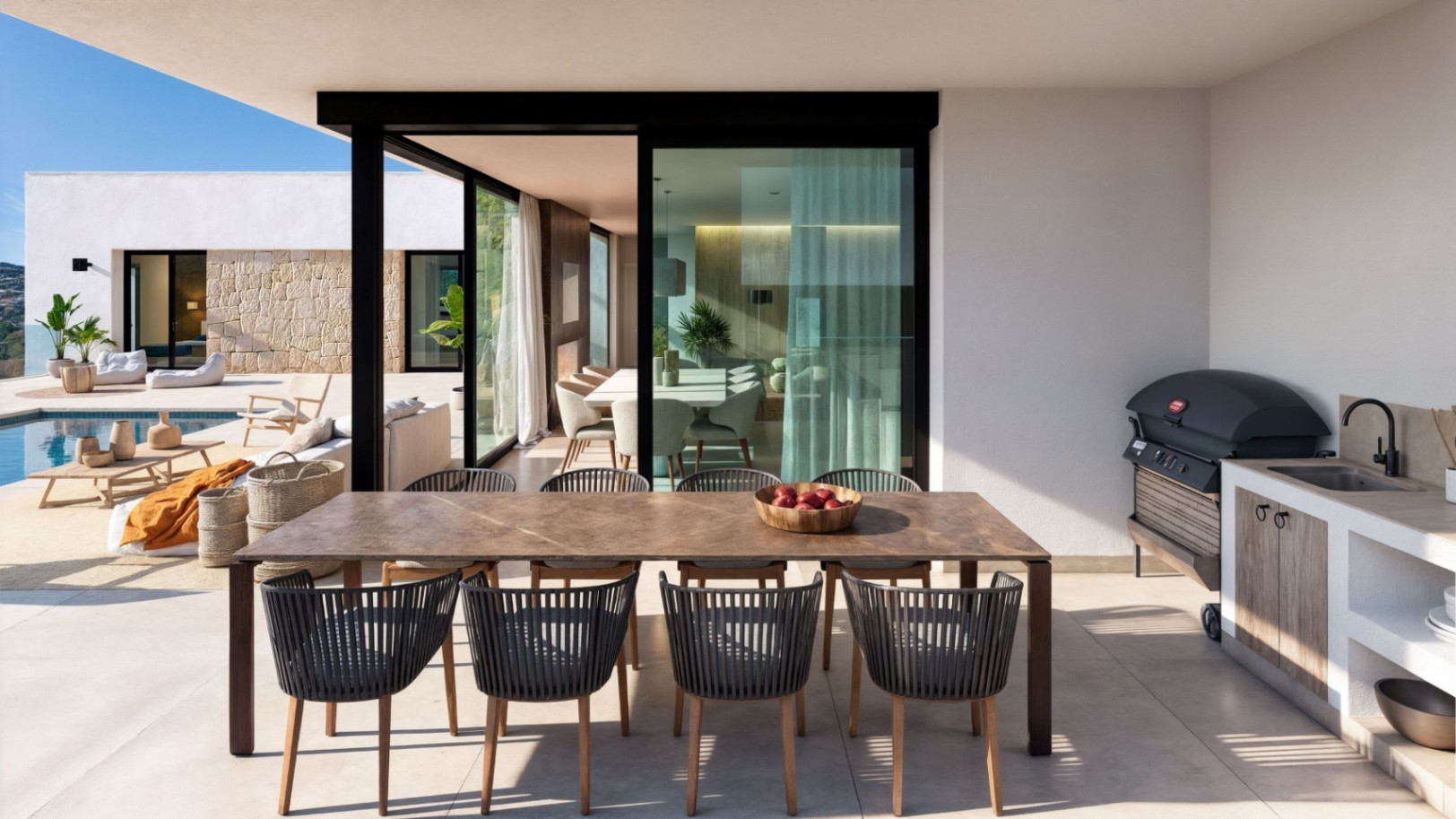 Terraza cubierta con mesa de comedor de madera, sillas de cuerda modernas y cocina exterior equipada con barbacoa y fregadero junto a la zona de piscina.