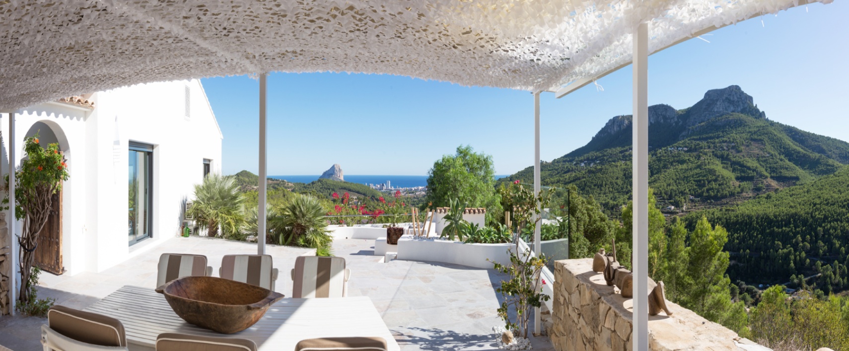 Terraza con pérgola blanca y sombreado de camuflaje, zona de comedor exterior y vistas panorámicas al mar Mediterráneo, el Peñón de Ifach y las montañas.
