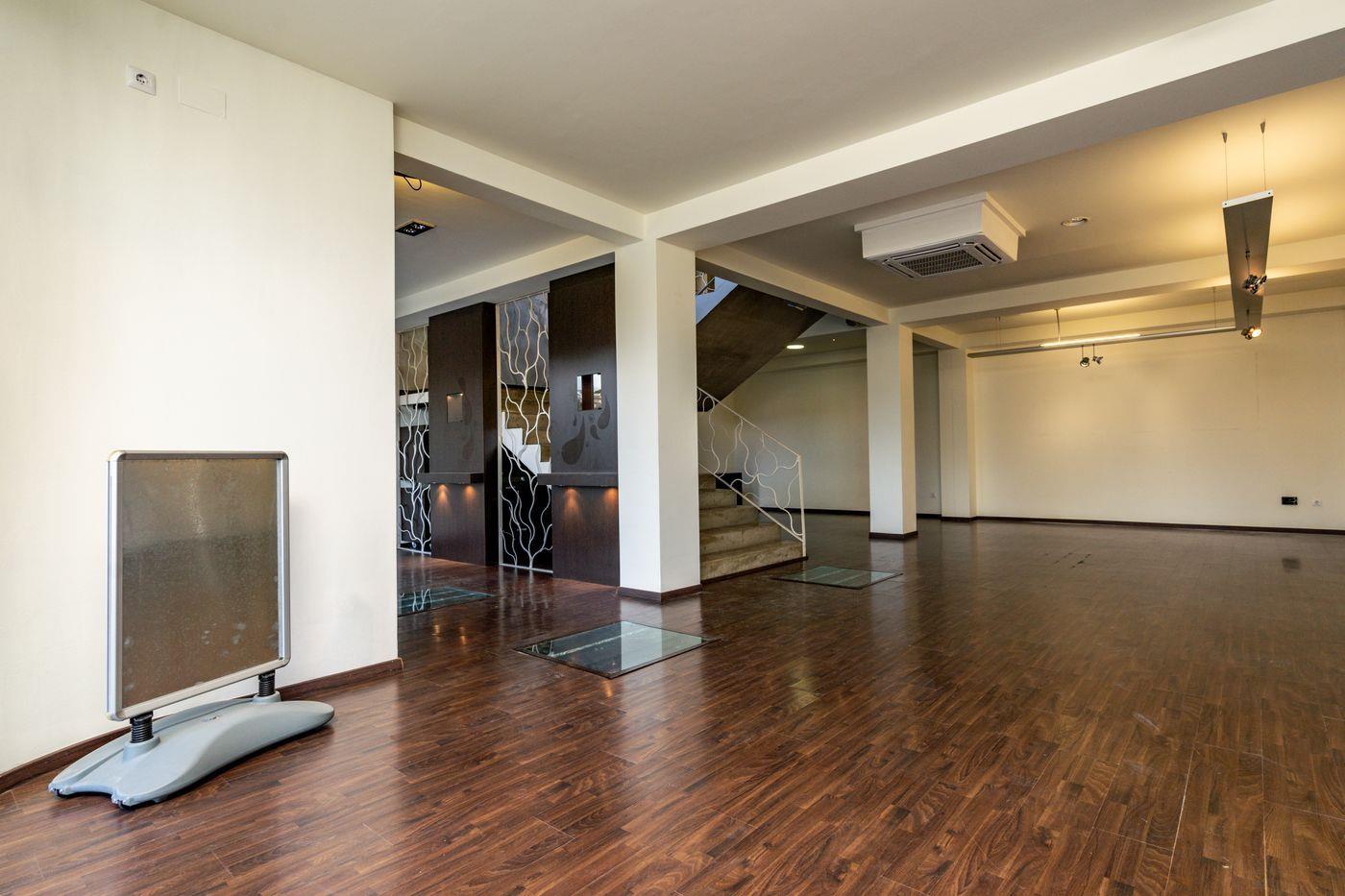 Amplio espacio diáfano con suelos de madera oscura, inserciones de cristal en el suelo y paneles decorativos. Incluye aire acondicionado central y escalera con barandilla blanca.