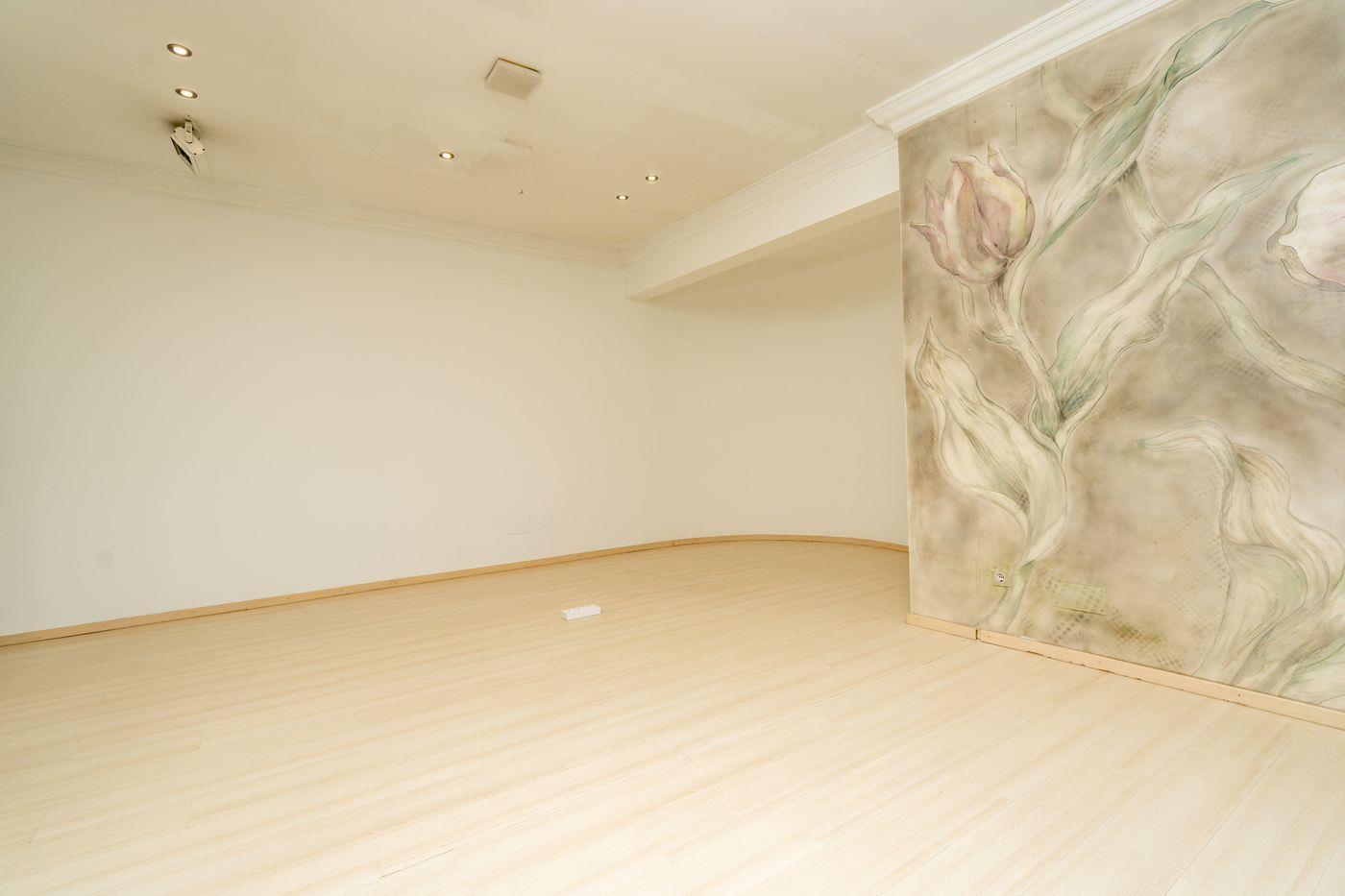 Habitación diáfana con suelo de madera clara, focos empotrados en el techo y un mural decorativo de tulipanes en la pared lateral.