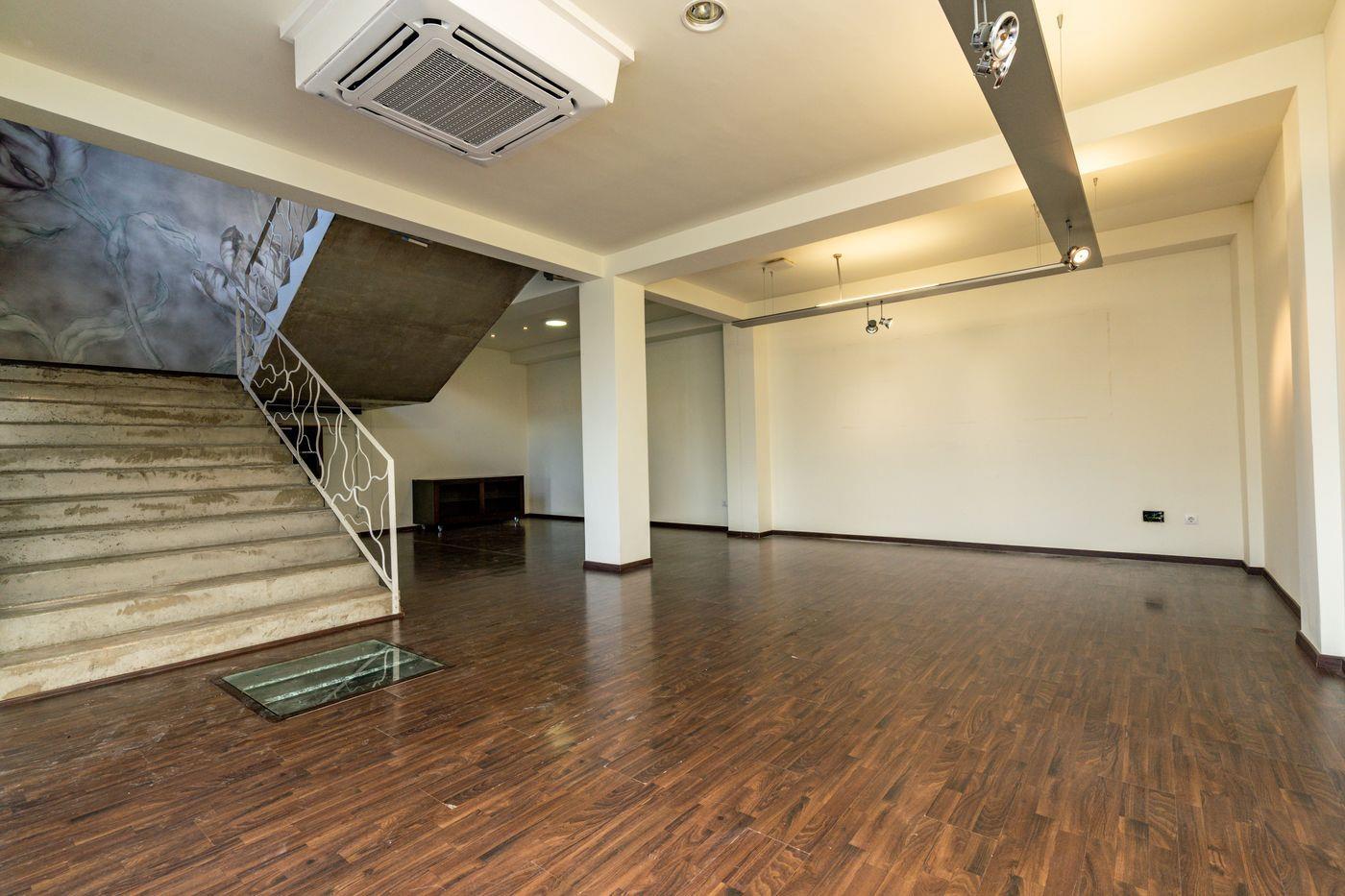 Interior diáfano con suelos de madera oscura, escalera de piedra con barandilla blanca ornamental y climatización integrada en el techo.