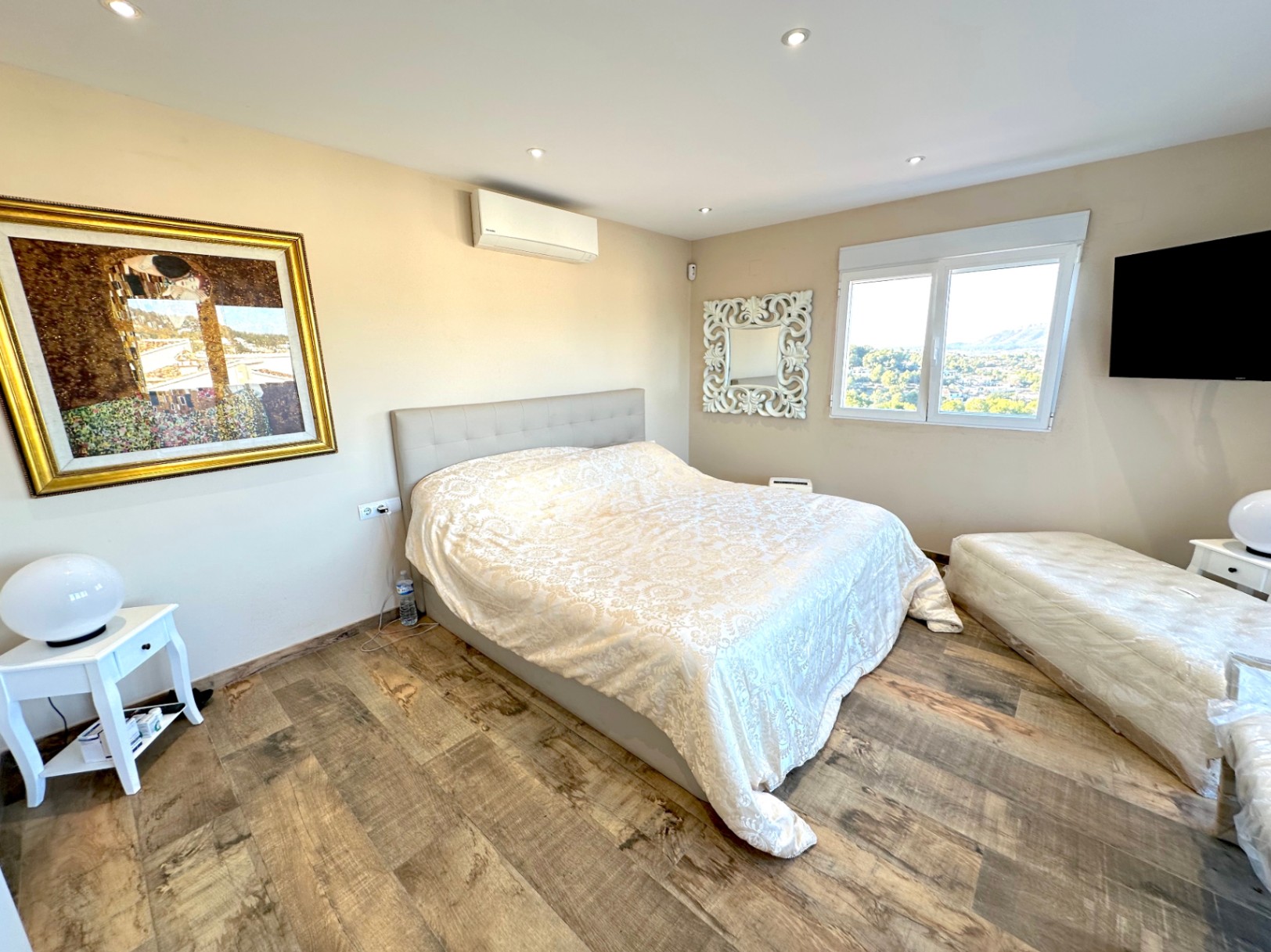 Dormitorio con suelos cerámicos de imitación madera, aire acondicionado y ventana con vistas al Montgó. Dispone de iluminación LED empotrada y mobiliario contemporáneo.