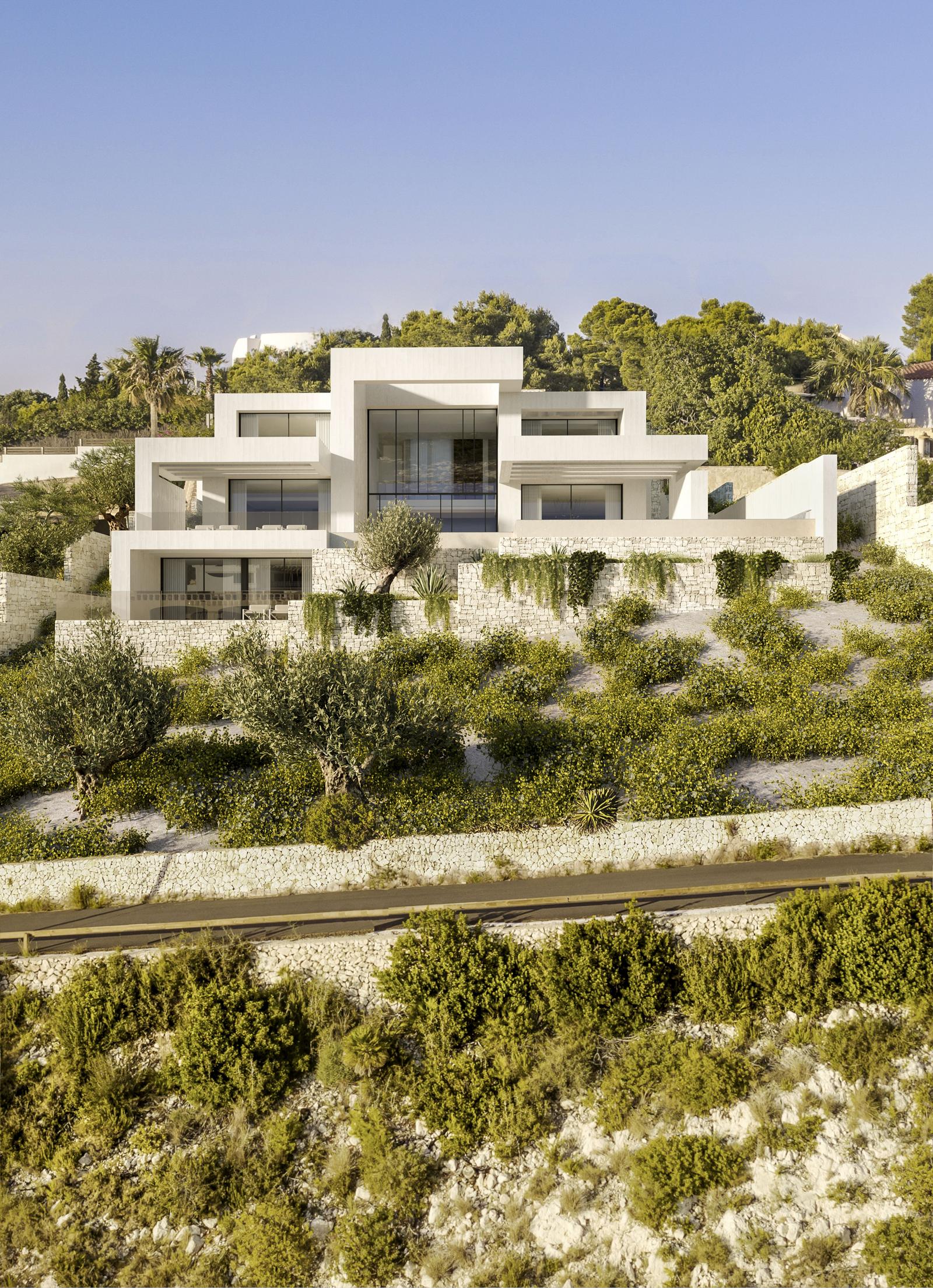 Villa moderna de varios niveles en Jávea con fachada geométrica blanca, muros de piedra seca escalonados y paisajismo mediterráneo integrado con olivos.