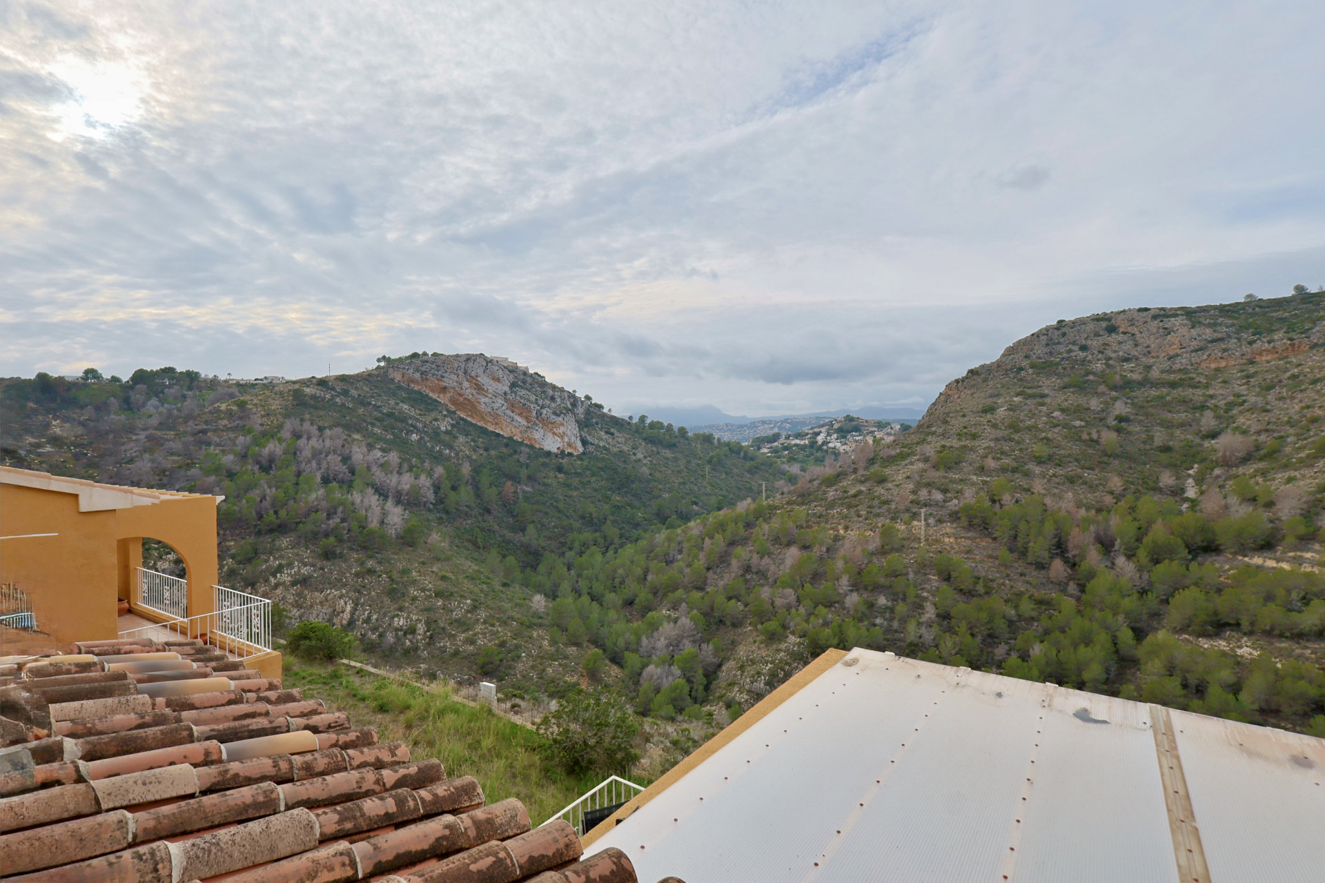 Vistas panorámicas al valle con vegetación mediterránea, destacando los tejados de teja tradicional y la arquitectura de arcos de la propiedad.