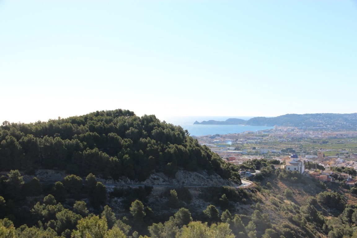 Vistas panorámicas desde la propiedad hacia el valle de Jávea, el mar Mediterráneo y el casco urbano con su emblemática cúpula azul bajo un cielo despejado.
