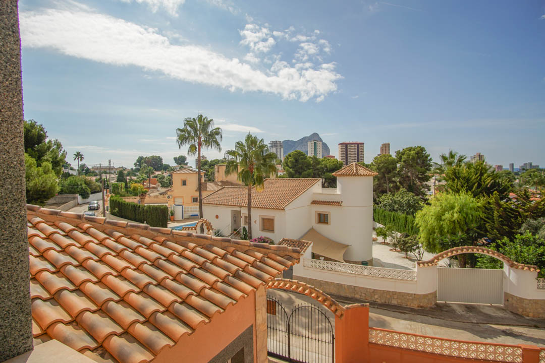 Vista panorámica desde la planta superior que muestra los tejados de terracota, el entorno residencial con palmeras y el Peñón de Ifach al fondo bajo un cielo despejado.